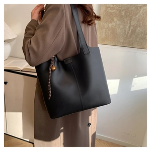 Sac cabas minimaliste en cuir noir avec cordon tressé et pendentif doré décoratif