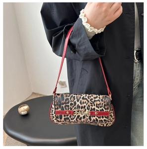 Close-up of leopard print baguette bag with red strap and gold horsebit detail