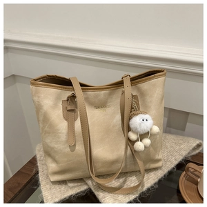 Detail of beige tote bag with Tidal dry bags text and brown leather handles with plush charm