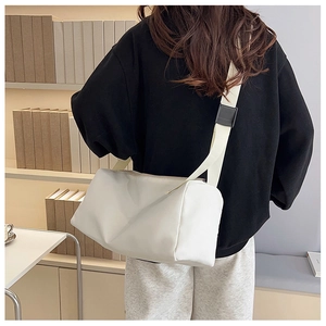 Sac à bandoulière en nylon blanc porté par un mannequin dans un intérieur moderne