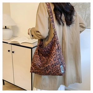 Detail of leopard print tote bag with adjustable shoulder strap and metal eyelet accents