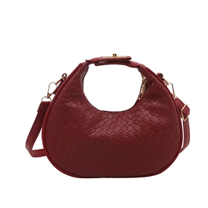 Dark red woven crescent handbag with gold hardware and adjustable strap on white background