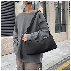 Gros plan d'un sac bandoulière en nylon noir porté par un mannequin dans une rue urbaine
