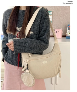 Beige nylon crescent crossbody bag with small round coin purse shown in use on model