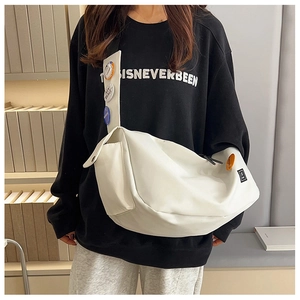Detail of white nylon messenger bag with decorative patches and spacious interior