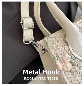 Close-up of silver metal hardware and floral lace embroidery on a beige woven bag