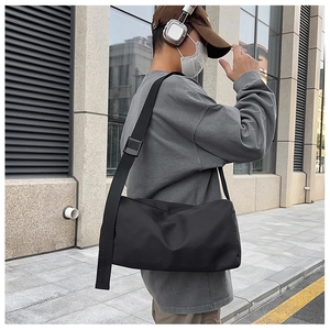 Détail de la bandoulière réglable et du tissu en nylon du sac messager noir sur modèle