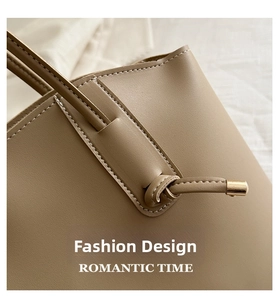Detailed close-up of khaki tote bag featuring reinforced stitching and gold metal accents