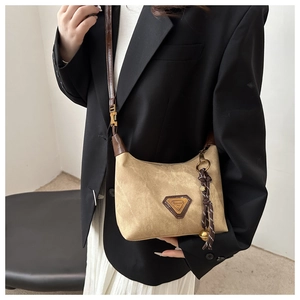 Detailed close-up of a khaki crescent bag with brown leather strap and triangle logo charm