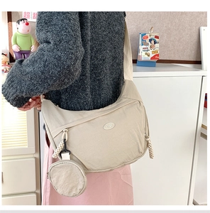 Detail of beige nylon crescent crossbody bag with a round coin pouch and logo patch