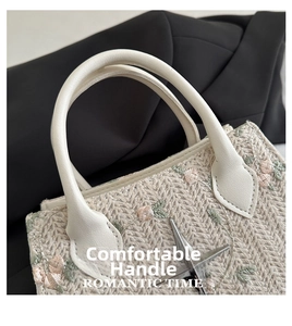 Detailed embroidery of pink flowers and green leaves on a beige woven straw handbag