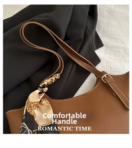 Close-up of brown leather tote bag handle with vintage printed silk scarf detail