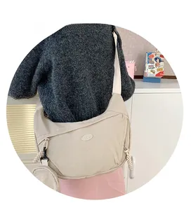 Detail of cream nylon crossbody bag with detachable round pouch and woven zipper pulls