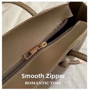 Close-up of smooth gold metal zipper closure and stitching on khaki leather tote bag
