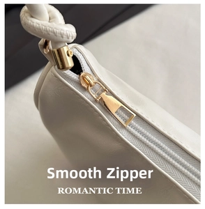 Detail of premium beige leather bag featuring golden smooth zipper and knotted strap