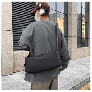 Vue de rue d'un sac messager en nylon noir porté en bandoulière par un mannequin en ville