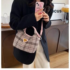 Borsa tote retrò a quadri con finiture rosa e logo dorato, indossata con una giacca nera