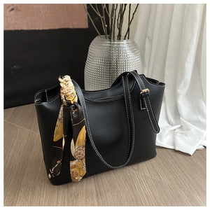 Detail of black tote bag featuring white contrast stitching and decorative floral silk scarf