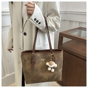 Detail of vintage brown tote bag with Tidal dryness text and fluffy charm on a model