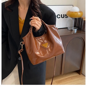 Dettaglio borsa shopper marrone con logo a triangolo in metallo e cuciture fini