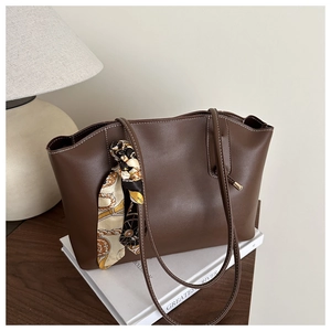 Detail of deep brown tote bag with white contrast stitching and decorative silk scarf