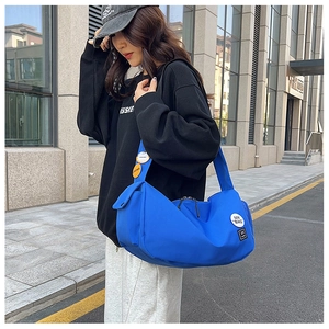 Detail of Klein Blue nylon messenger bag featuring white embroidery and street fashion patches