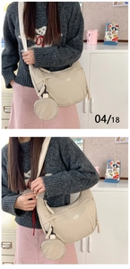 Detail of beige nylon crescent bag with woven rope zipper and mini round pouch charm
