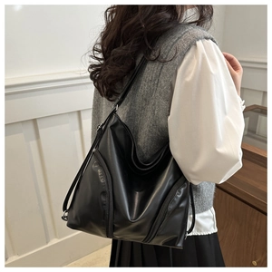 Detailed view of the side vertical zippers on a black glossy leather hobo tote bag