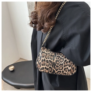 Close-up of leopard print crescent bag with golden chain strap on a black outfit