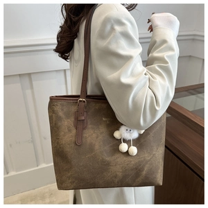 Detail of retro brown tote bag with oily leather texture and plush monster charm