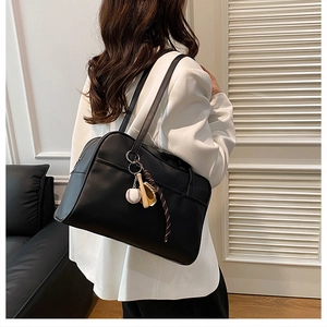 Detail of black tote bag with unique baseball accessories on white blazer model