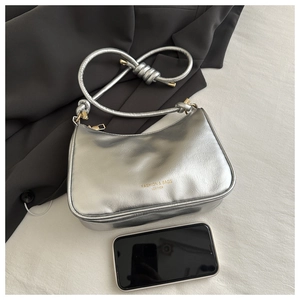 Silver baguette bag detail with metallic crinkle finish and gold lettering