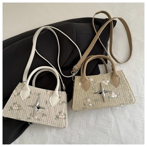 Detail of hand-woven crossbody bag with delicate floral embroidery and star charm