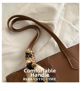 Close-up of brown tote bag showing checkered texture, reinforced stitching and silk scarf