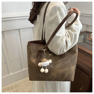Detail of vintage brown tote bag with gold lettering and cute plush charm on shoulder