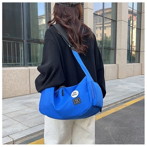 Royal blue nylon messenger bag with adjustable strap shown in a street style perspective
