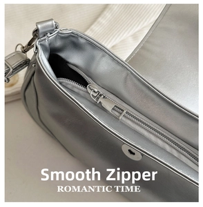 Detailed close-up of smooth silver zipper and metallic magnetic clasp on a saddle bag