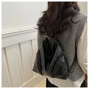 Detail view of the black soft leather backpack featuring vertical side zipper pockets