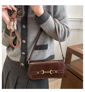 Close-up of vintage brown leather shoulder bag with a gold horsebit buckle detail