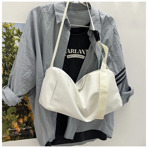 Vue détaillée du grand sac bandoulière en nylon blanc suspendu sur un portant minimaliste