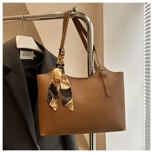 Brown leather tote bag detail featuring a decorative printed silk scarf on handle