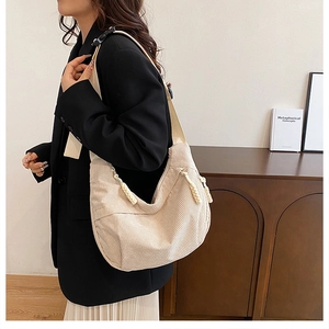 Close-up of beige corduroy crossbody bag with wide strap and moon shape design