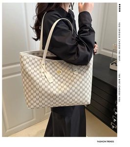 Detail of monogram pattern tote bag with golden metal logo and leather shoulder strap
