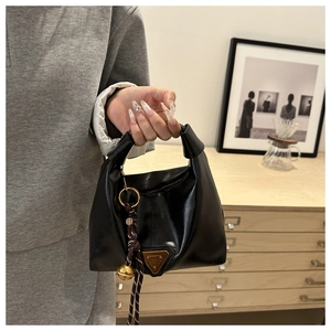 Chic black faux leather handbag with gold plaque and decorative charm in a cozy setting