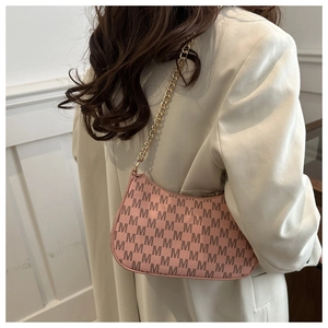 Detail of pink monogram crescent bag featuring a gold chain strap and vintage pattern