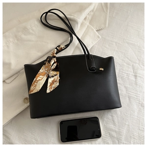 Detail of black tote bag with white stitching and decorative silk scarf accessory