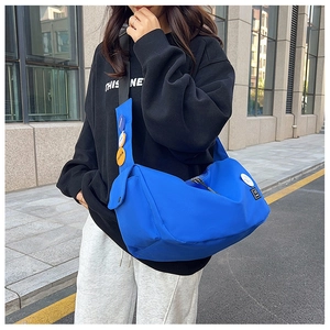 Detail of bright blue nylon messenger bag with decorative badges on a black hoodie