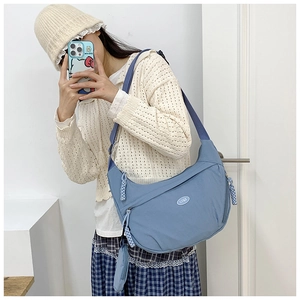 Blue nylon crossbody dumpling bag detail with adjustable strap and coin purse accessory