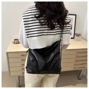 Detailed back view of model wearing a black soft PU leather tote bag with vertical zippers