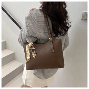 Brown tote bag with patterned silk scarf shown on model for size perspective